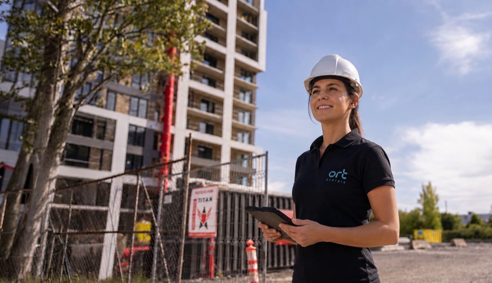 Ingénieure d’ORT Énergie avec une tablette devant un immeuble en construction